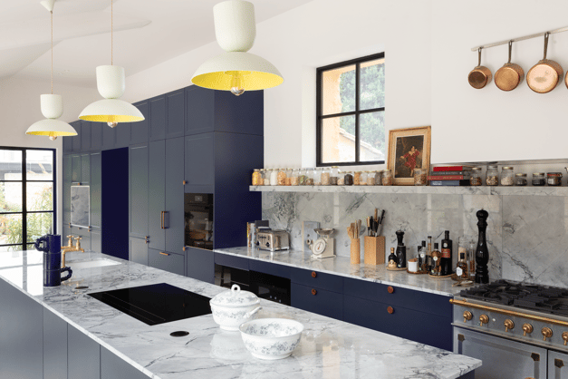 Cuisine sur mesure Perene Réunion avec façades bleu profond, îlot central en marbre, électroménager intégré et finitions haut de gamme.