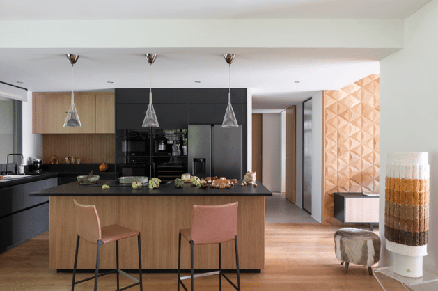 Cuisine sur mesure Perene Réunion avec îlot central noir, façades en bois, mobilier contemporain et électroménager intégré.