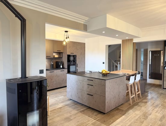 Cuisine ouverte à Vendargues avec îlot central, façades effet béton ciré, plan de travail en granit noir et tasseaux de bois.
