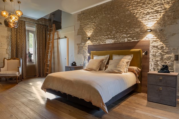 Chambre de caractère avec murs en pierre, tête de lit et chevets sur mesure, réalisée par PERENE Caen à Saint-Contest.