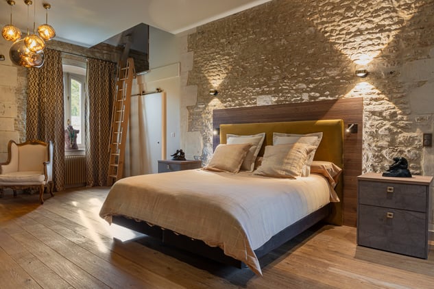 Chambre de caractère avec murs en pierre, tête de lit et chevets sur mesure, réalisée par PERENE Caen à Saint-Contest.