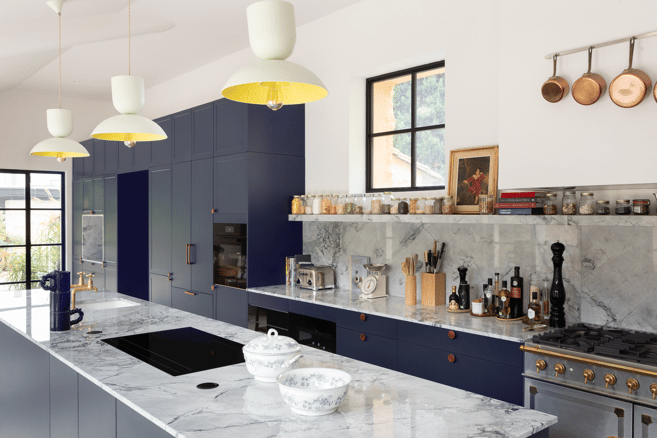 Cuisine sur mesure Perene Réunion avec façades bleu profond, îlot central en marbre, électroménager intégré et finitions haut de gamme.