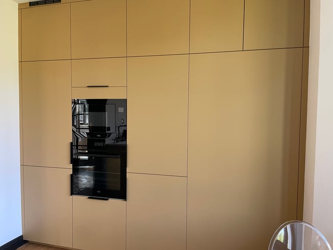 Cuisine sur mesure contemporaine en finition Camel verni avec plan de travail et crédence marbrée clair à Saverne