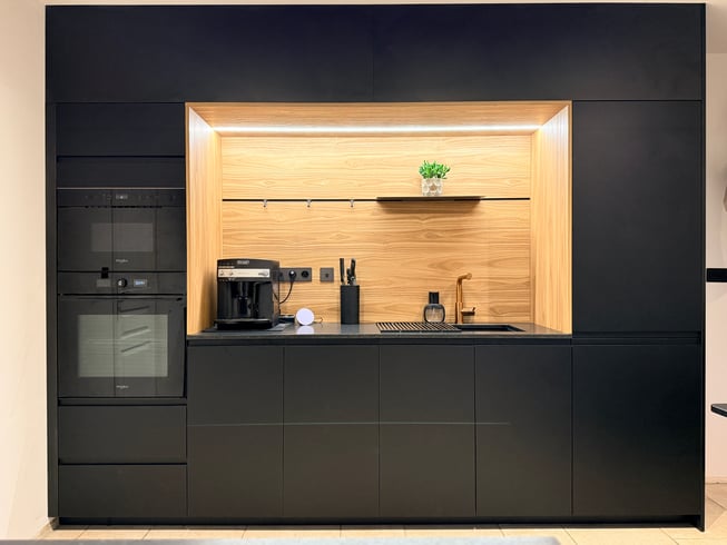 La niche en chêne Okobo, éclairée en LED, s'impose comme un écrin lumineux dans l'écrin noir mat.
