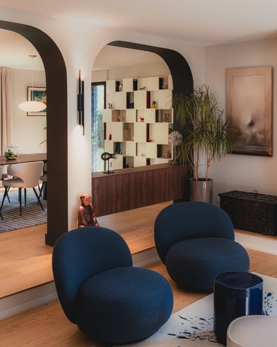 Agencement intérieur sur mesure réalisé par Perene Caen avec arches architecturales, bibliothèque design et séparation de pièce en noyer.