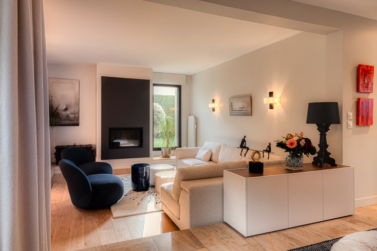 Salon contemporain avec meuble de séparation sur mesure, cheminée intégrée et mobilier haut de gamme réalisé par PERENE Caen.