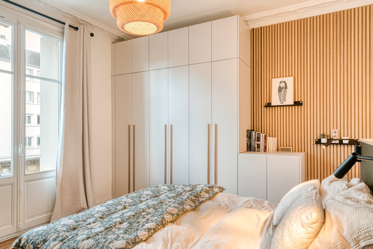 Dressing sur mesure dans une chambre parentale avec façades blanches toute hauteur, poignées bois et claustra décoratif réalisé par PERENE Caen.