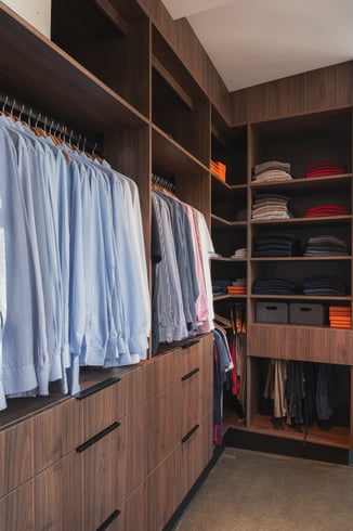 Walk-in dressing sur mesure avec penderies, tiroirs et étagères en finition noyer.