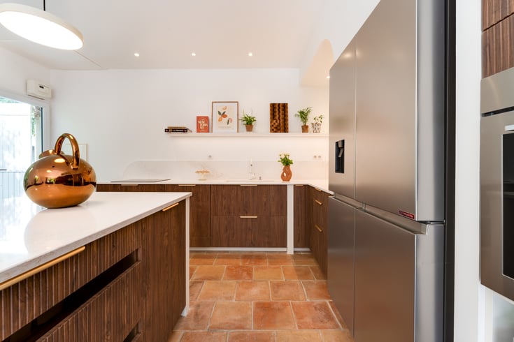 Cuisine en bâti avec façades rainurées en noyer Opéra, îlot central et plan de travail en quartz.