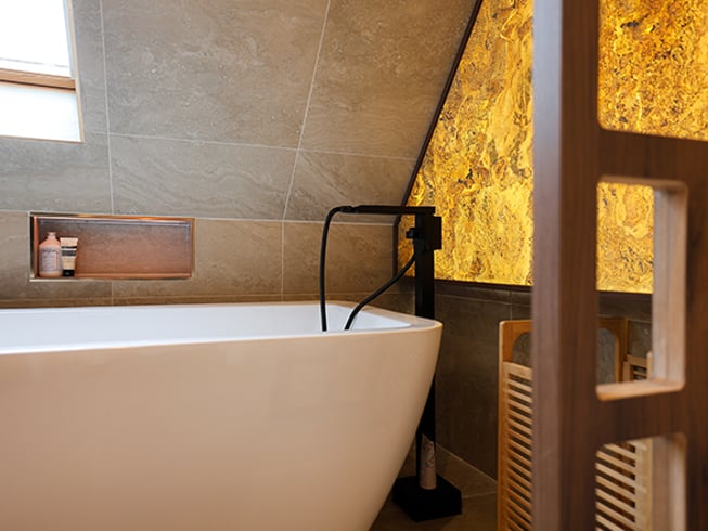 Zoom sur la baignoire îlot avec sa niche encastrée au mur carrelé