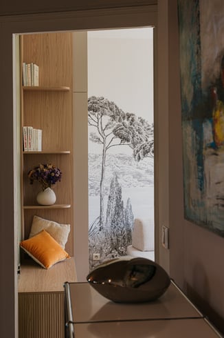 Perspective entre la salle d’eau et le salon aménagé avec des rangements et une banquette sur mesure. Perspective entre la salle d’eau et le salon aménagé avec des rangements et une banquette sur mesure.