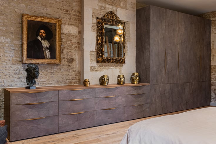 Dressing toute hauteur et commode sur mesure aux façades sombres, associés à un mur en pierre.
