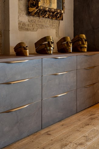 Rangements bas sur mesure aux façades sombres et poignées dorées dans une chambre de caractère.