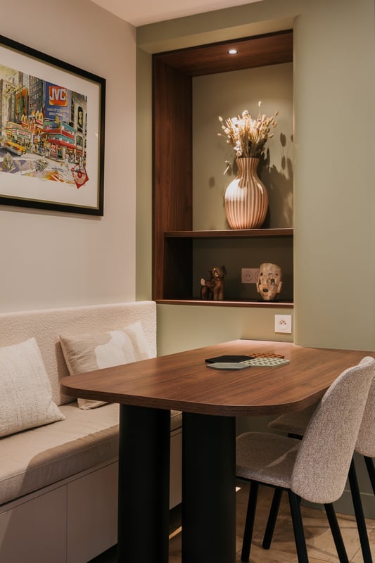 Coin repas sur mesure avec banquette intégrée, table en noyer et niche décorative éclairée réalisé par PERENE Caen.
