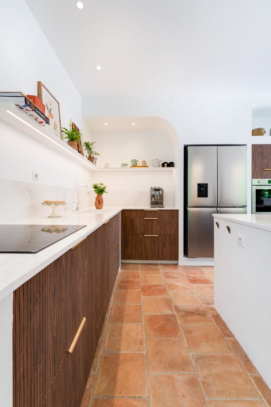 Cuisine en bâti avec façades rainurées en noyer Opéra, îlot central et plan de travail en quartz.
