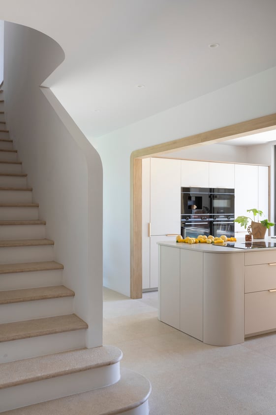 Cuisine-vue-sur-escalier-et-ilot-central-blanc-bois