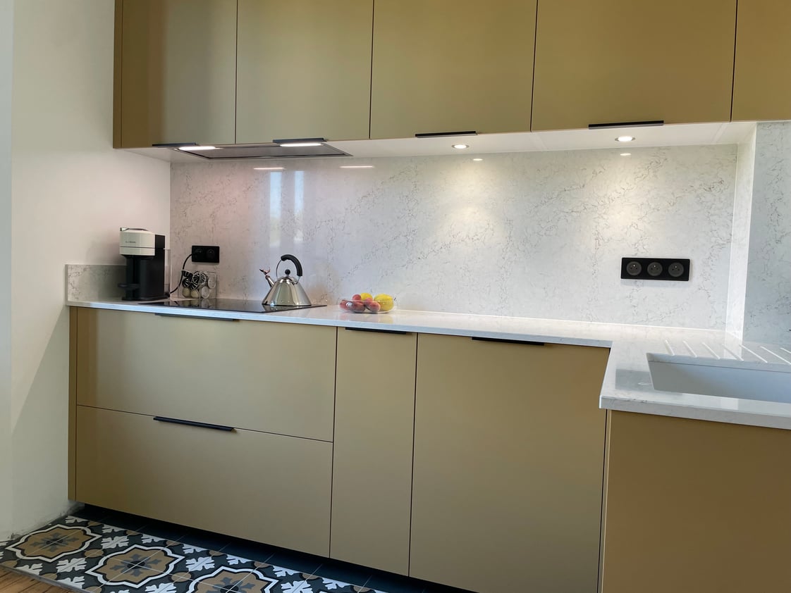 Cuisine sur mesure contemporaine en finition Camel verni avec plan de travail et crédence marbrée clair à Saverne