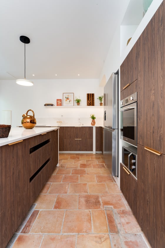 Cuisine en bâti avec façades rainurées en noyer Opéra, îlot central et plan de travail en quartz.
