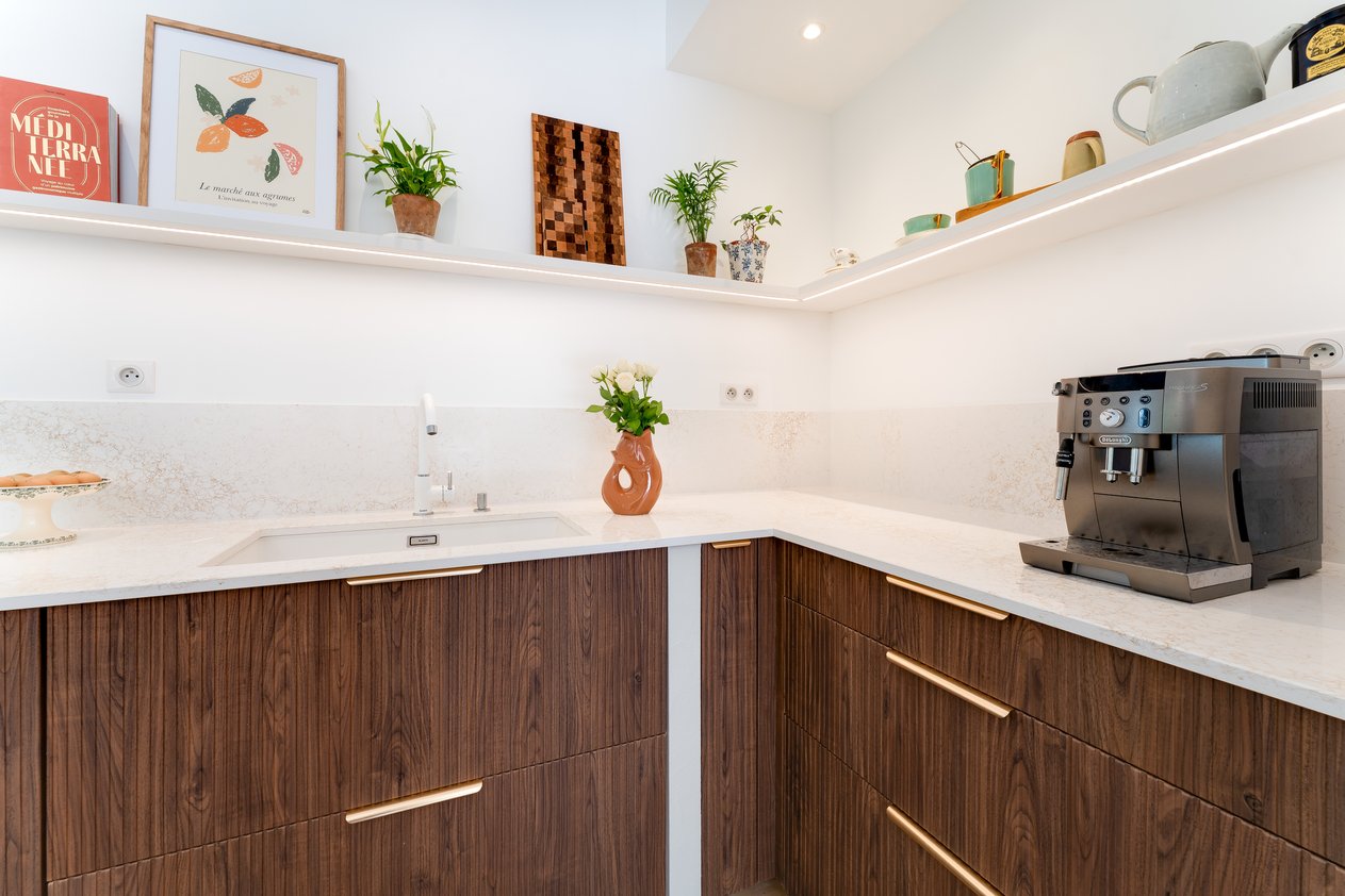 Cuisine en bâti avec façades rainurées en noyer Opéra, îlot central et plan de travail en quartz.