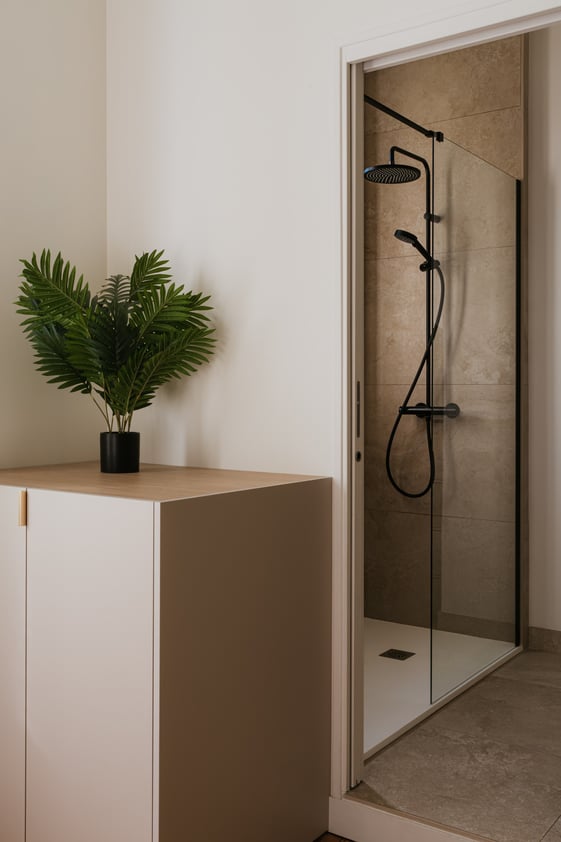 Salle d’eau aux tons naturels avec douche vitrée, robinetterie noire et meuble de rangement. Salle d’eau aux tons naturels avec douche vitrée, robinetterie noire et meuble de rangement.