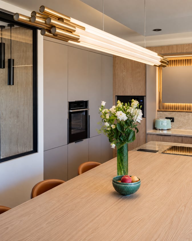 Cuisine contemporaine aux tons naturels, associant bois clair, mobilier épuré et verrière noire. Une grande table centrale, entourée de chaises en cuir cognac, structure l’espace, sublimé par des éclairages indirects chaleureux. Cuisine contemporaine aux tons naturels, associant bois clair, mobilier épuré et verrière noire. Une grande table centrale, entourée de chaises en cuir cognac, structure l’espace, sublimé par des éclairages indirects chaleureux.