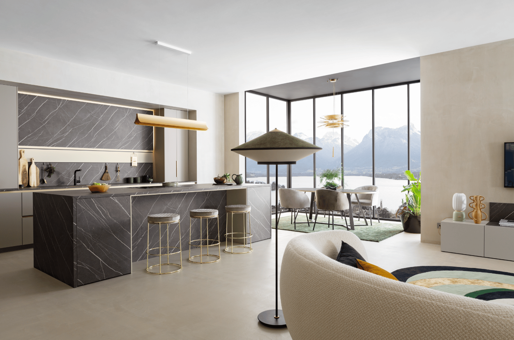Cuisine sur mesure Perene Réunion avec îlot central en pierre, finitions haut de gamme, mobilier contemporain et large baie vitrée offrant une vue panoramique.