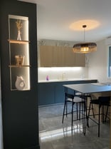 Cuisine avec un ilot en vert, détails de bois et niche decorative
