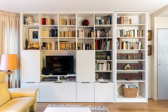 La bibliothèque habille tout un grand mur et abrite la télévision, des niches pour les livres ou la décoration mais également des tiroirs pour les objets à ranger. 