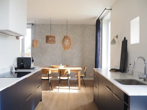 Très bel ensemble entre le bleu profond des meubles, le blanc du plan de travail et le bois du parquet et de la table de salle-à-manger avec le rappel trés réussi des luminaires.