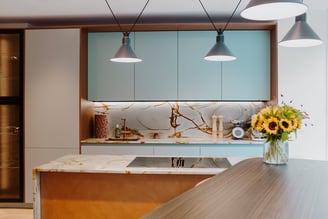 Cuisine sur mesure contemporaine avec façades bleu céladon, plan de travail en pierre naturelle et finitions en bois réalisée par Perene Réunion.