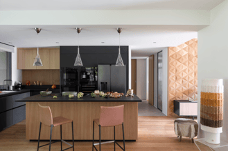 Cuisine sur mesure Perene Réunion avec îlot central noir, façades en bois, mobilier contemporain et électroménager intégré.