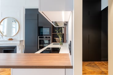 Chic et élégante, cette cuisine ouverte offre tous les rangements nécessaires tout en s'intégrant parfaitement au milieu des cheminées, parquet, moulures et autres détails très haussmanniens. 