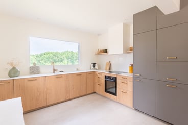 La cuisine se compose d'un linéaire bas en forme de L. Depuis l'évier, situé sous une grande baie vitrée, la vue est dégagée sur le jardin.