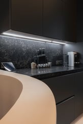 Détail d’un plan de travail minéral noir et meubles de cuisine haut de gamme aux finitions mates dans une cuisine contemporaine à Deauville.