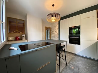 Cuisine avec ilot central vert et vue sur les verrière décorative