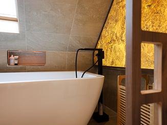 Zoom sur la baignoire îlot avec sa niche encastrée au mur carrelé