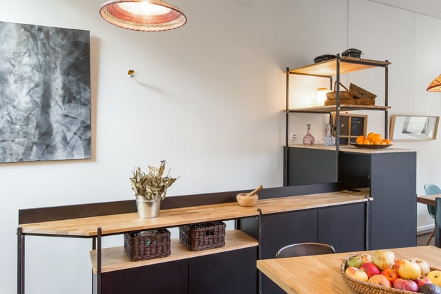 Vue d'ensemble sur cette cuisine fonctionnelle, lumineuse grâce au patio et à plusieurs fenêtres qui donnent sur une cour .