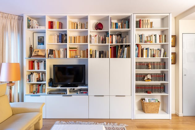 La bibliothèque habille tout un grand mur et abrite la télévision, des niches pour les livres ou la décoration mais également des tiroirs pour les objets à ranger. 