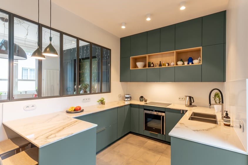 Séparée de la salle-à-manger par une verrière, la cuisine ne comporte que des meubles bas dans sa partie visible depuis celle-ci.