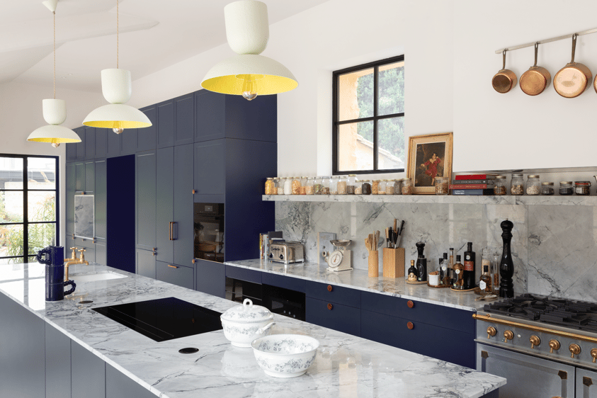 Cuisine sur mesure Perene Réunion avec façades bleu profond, îlot central en marbre, électroménager intégré et finitions haut de gamme.