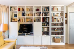 La bibliothèque habille tout un grand mur et abrite la télévision, des niches pour les livres ou la décoration mais également des tiroirs pour les objets à ranger. 
